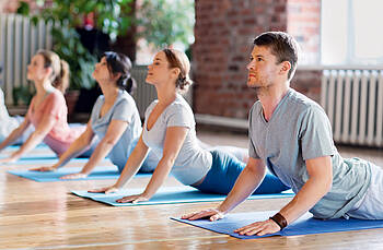 Concordia Yoga Cobra Yogagruppe, die auf Matten eine Übung durchführt