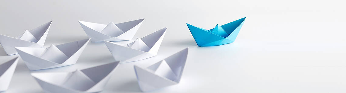 Leitfäden Viele weiße und ein blaues Papierschiff