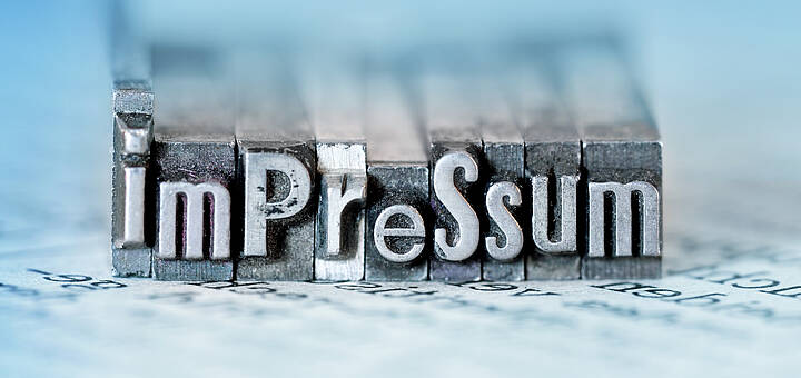 Impressum Wort „Impressum“ als Metallstempel dargestellt