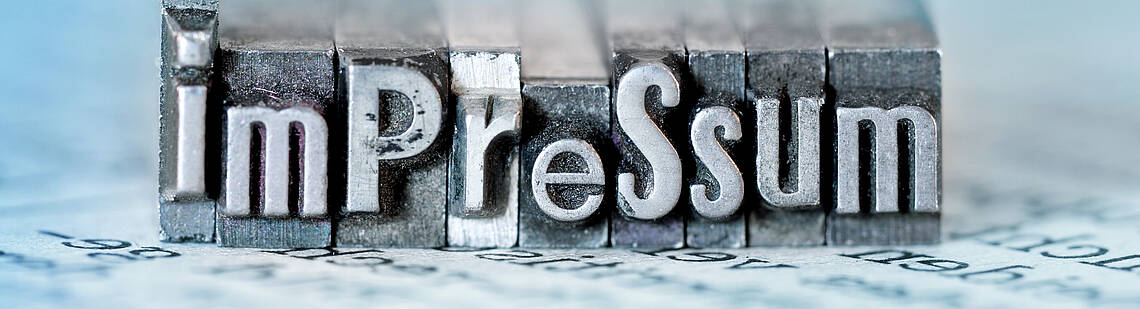 Impressum Wort „Impressum“ als Metallstempel dargestellt