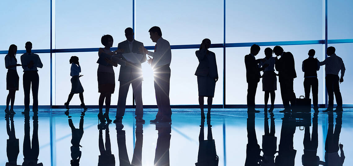 Kopfzeile „Wir über uns – Gremien“ Business Meeting einer Personengruppe mit Sonne im Gegenlicht