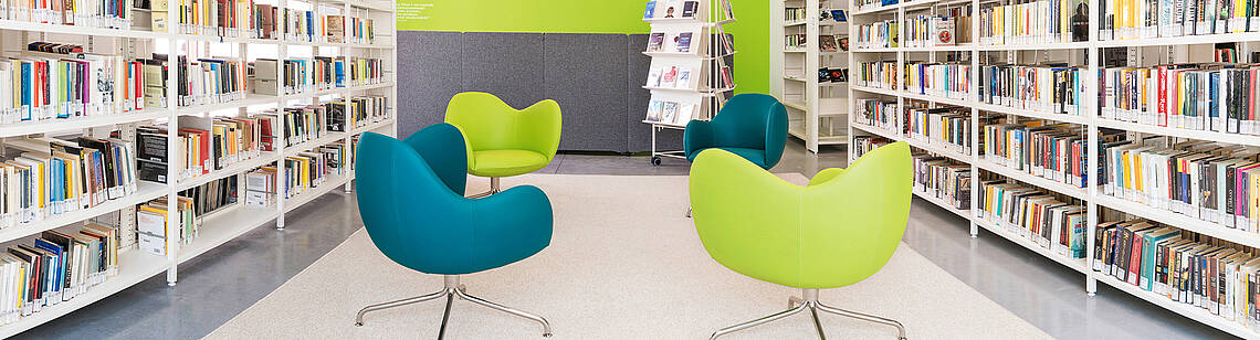 vis a vis Bücherregale, zwischen denen Sessel stehen