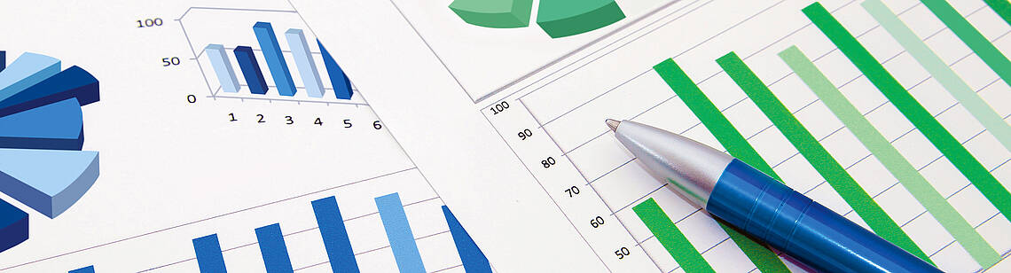 Kugelschreiber auf zwei Blättern mit Kreis- und Balkendiagrammen