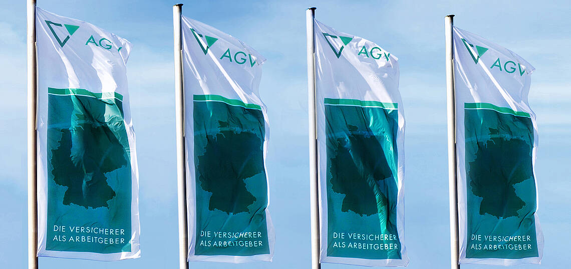 Kopfzeile „Wir über uns – Aufgaben“ Vier Fahnen des AGV wehen im Wind