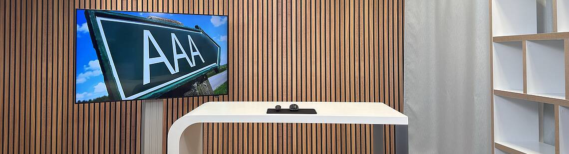 Leeres Studio mit einem Monitor im Hintergrund der ein Bild mit dem „Triple A“ zeigt