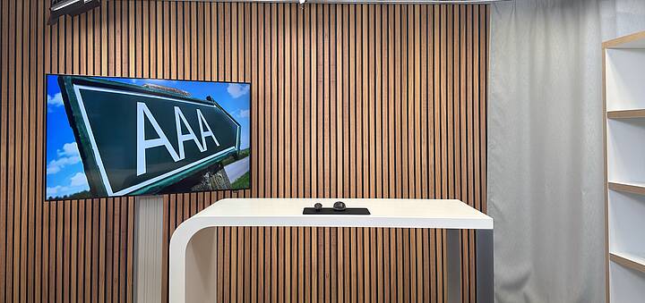 Leeres Studio mit einem Monitor im Hintergrund der ein Bild mit dem „Triple A“ zeigt